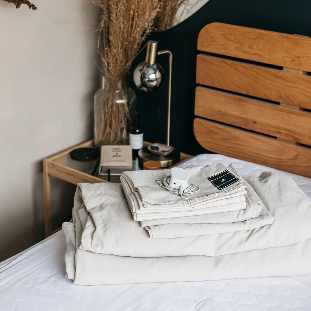 Tapis et drap de grounding pour mieux dormir, posés sur un lit en bois dans une chambre zen